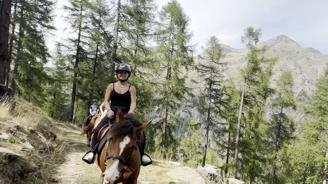 Cavalieri su un sentiero di montagna tra i larici